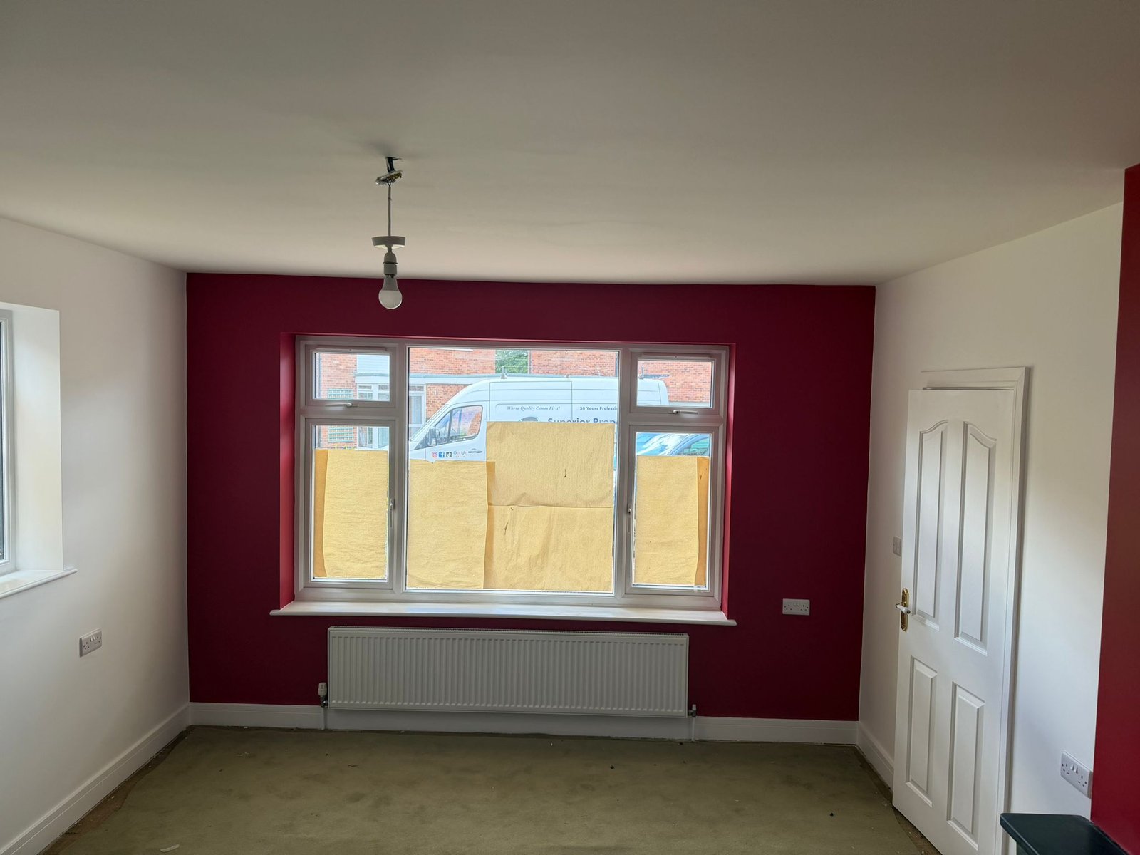 A lounge redecorated in custom bold red feature wall and light grey main walls.